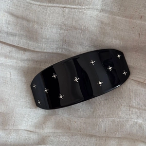 Détail d'une pince à cheveux rectangulaire noire brillante ornée de strass blancs fins