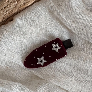 Close-up of burgundy velvet BB hair clip with white dots and sparkly silver stars