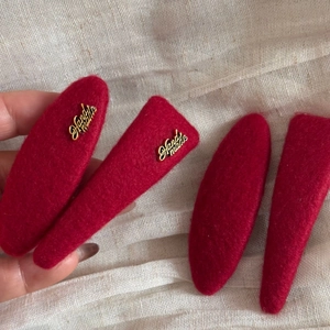 Detail of red wool felt hair clips with golden Handmade lettering for autumn and winter