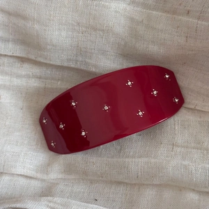 Détail de la barrette bordeaux avec strass étincelants sur fond de tissu texturé