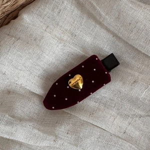 Close-up of burgundy velvet hair clip with white polka dots and gold heart detail
