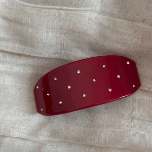 Détail d'une barrette bordeaux avec strass et finition résine sur lin