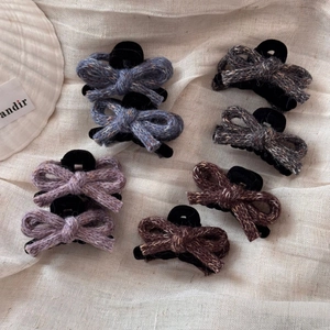 Detail of knitted bow hair clips in multiple colors on a soft linen background