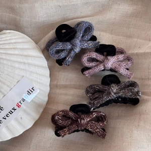 Detail of four knitted bow hair clips in blue, purple, and brown tones for autumn fashion