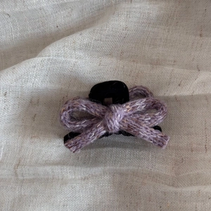 Detailed macro view of the purple knitted wool bow design on the black hair claw clip