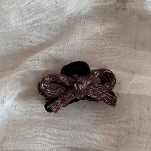 Detailed view of handmade knitted bow hair claw with vintage dark brown wool texture
