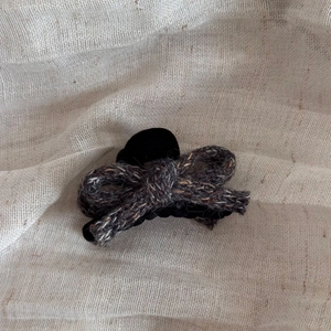 Detailed view of the dark grey knitted wool bow hair claw with soft fabric texture