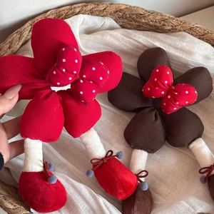 Vue détaillée de poupées en peluche florales rouges et marron avec nœuds à pois en panier