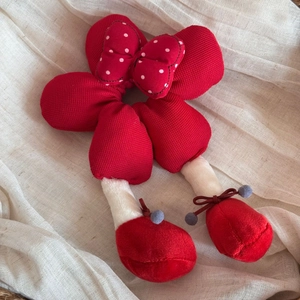 Gros plan d'un chouchou en peluche à fleurs rouges avec nœud à pois et détails de jambes
