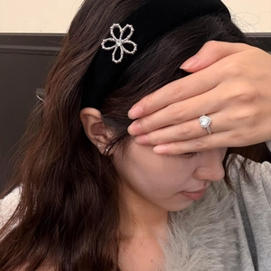 Detailaufnahme von schwarzem Samtstirnband mit glitzernden Blumen-Steinen und Herz-Zirkon-Ring