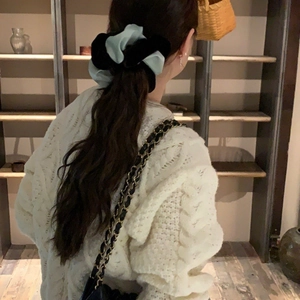 Detail of mint green and black velvet scrunchie worn on ponytail with cozy sweater