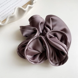 Détail d'un chouchou en soie plissée mauve foncé avec un lustre doux et élégant