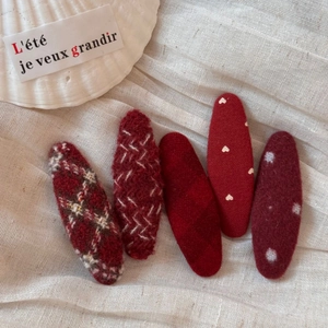 Macro detail of red knit BB hair clips featuring polka dots and heart patterns