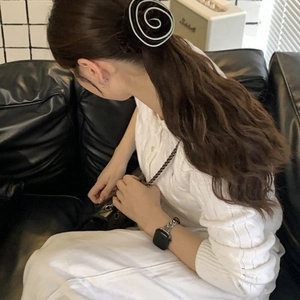 Close-up of a stylish black and white spiral hair scrunchie on a low ponytail