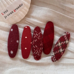 Set of five elegant red heart and polka dot fabric hair clips on cream gauze background