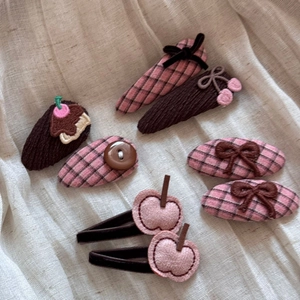 Detailed set of 7 girls' hair clips with pink bows and fabric textures on linen cloth