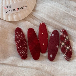 Close-up of five red fabric hair clips with heart, polka dot and plaid patterns