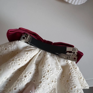Dettaglio del fiocco vintage in velluto bordeaux e pizzo ricamato con molletta a molla in metallo