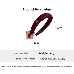 Detail view of burgundy knitted headband with golden animal charm and handmade label