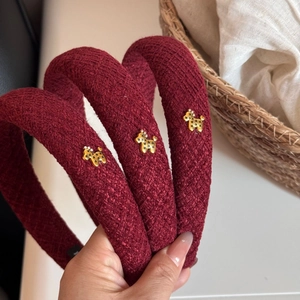 Detail of burgundy tweed headband featuring golden dog ornament and textured fabric