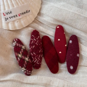 Close-up of five red fabric BB hair clips featuring plaid, dots, and knit textures