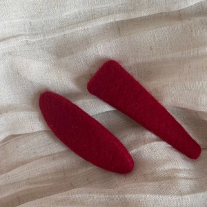 Close-up of red flocked fabric hair clips with polka dots on a beige linen background