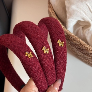 Close-up of three wine red tweed headbands with golden dog charms and star details