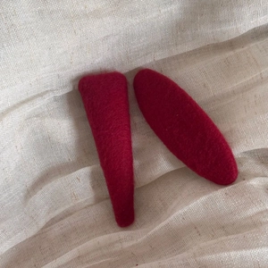Close-up of two red heart polka dot felt hair clips on beige textured fabric