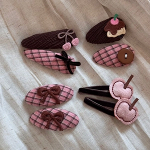 Detail of 6pcs cute hair clips with cherry, bow and button designs on soft beige fabric