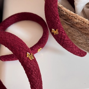 Close-up of red woven fabric headband with a small golden dog metal charm detail