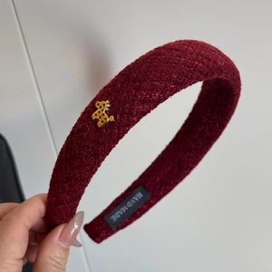 Close-up of red tweed woven headband featuring a golden bear charm and handmade label