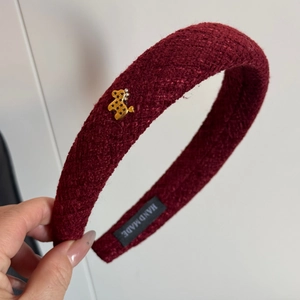 Detail of burgundy tweed headband showing golden bear charm with star pattern and gems
