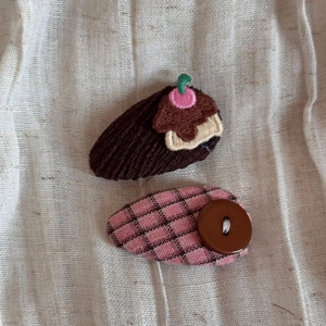 Detailed shot of handmade hair clips featuring pudding embroidery and button plaid fabric