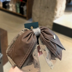 Detail of polka dot ribbon bow hair clip with leather texture and white stitching