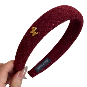 Red braided tweed headband with golden star-patterned bear charm and handmade label