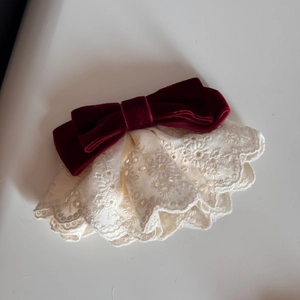 Dettaglio del fiocco in velluto bordeaux con volant in pizzo floreale bianco crema per capelli