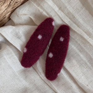 Close-up of wool polka dot hair clips in deep red on natural linen background