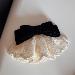 Dettaglio del fiocco in velluto con ricamo in pizzo bianco sulla molletta per capelli