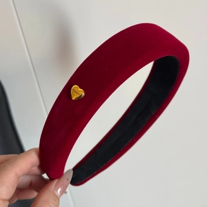 Macro shot of burgundy velvet headband showing gold heart buckle and thick padded texture