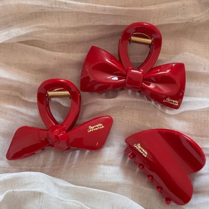 Elegant red bow hair claw clips and shark hair clip set with gold spring on beige fabric