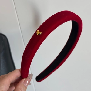 Detail of red velvet headband with golden heart charm and black non-slip lining