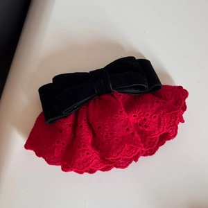 Dettaglio del ricamo in pizzo rosso e fiocco in velluto nero per fermaglio