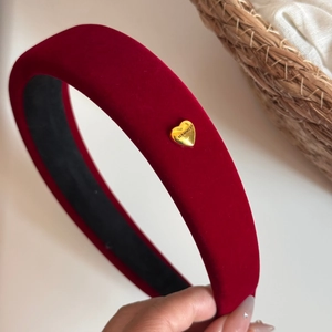 Detail of burgundy velvet headband showing a golden heart charm and soft sponge padding