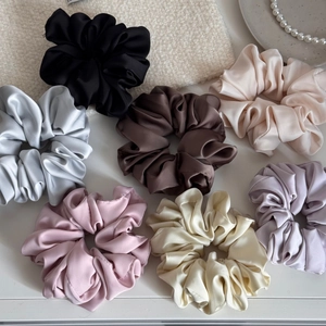 Chouchous en satin colorés disposés sur un fond texturé doux avec un collier de perles