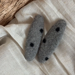 Detail of grey wool felt hair clips with black polka dots on textured linen background