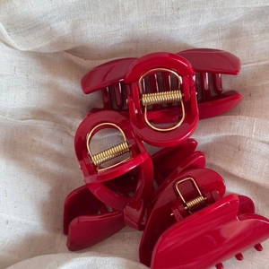 Detailed view of glossy red bow hair claws with durable golden springs on fabric