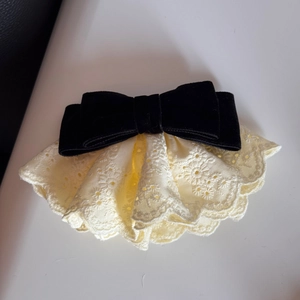 Dettaglio del fermaglio per capelli con fiocco in velluto nero con pizzo e ricami di girasole