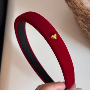 Macro view of red velvet headband with a polished gold heart-shaped metal ornament