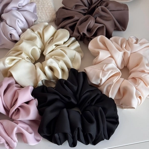 Chouchous en satin surdimensionnés en crème, noir et couleurs pastel sur fond blanc