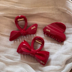 Detailed macro view of three red acrylic bow hair clips with gold spring mechanisms